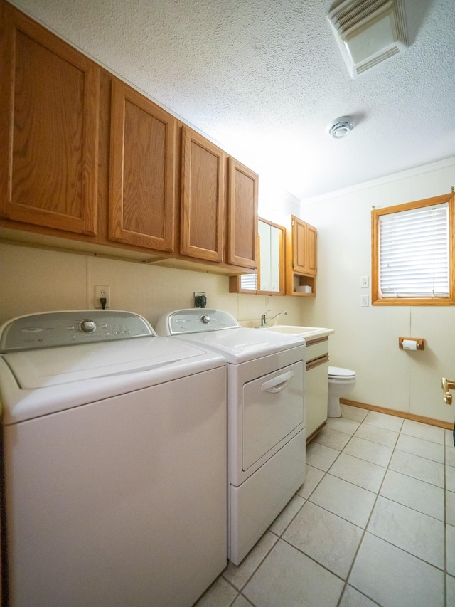 laundry area featuring baseboards, washer and clothes dryer, light tile patterned flooring, a textured ceiling, and a sink