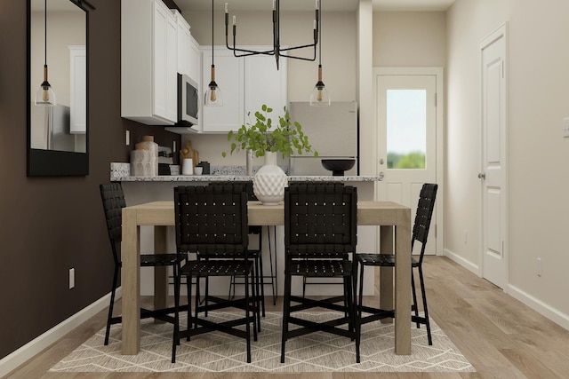 dining space with baseboards, light wood-style floors, and an inviting chandelier