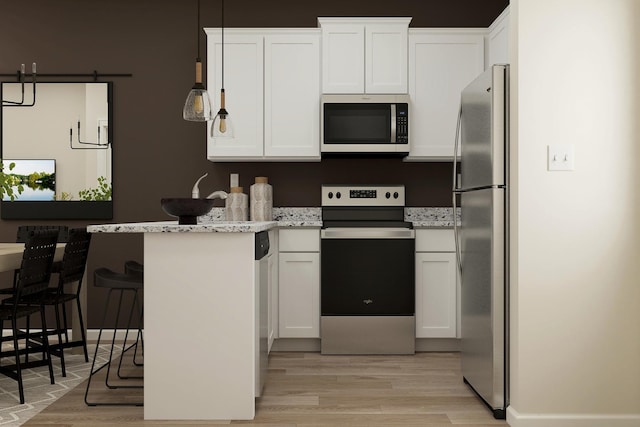 kitchen with light stone countertops, a breakfast bar, appliances with stainless steel finishes, white cabinetry, and light wood-type flooring