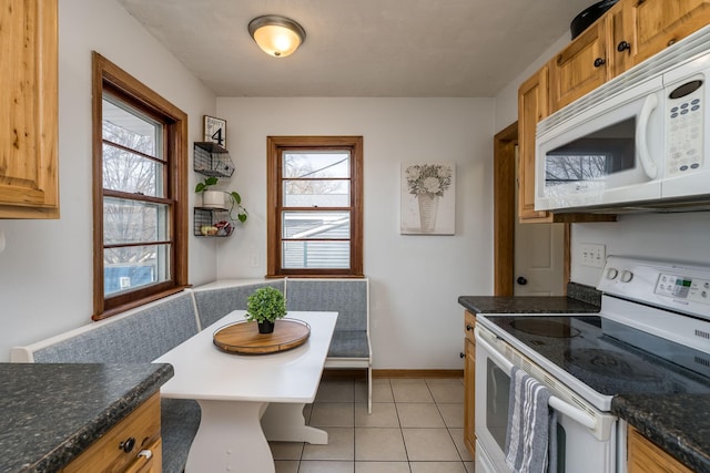 kitchen with a wealth of natural light, light tile patterned floors, white appliances, and breakfast area