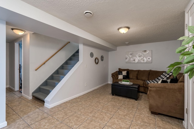 living room with stairs, light tile patterned floors, baseboards, and a textured ceiling