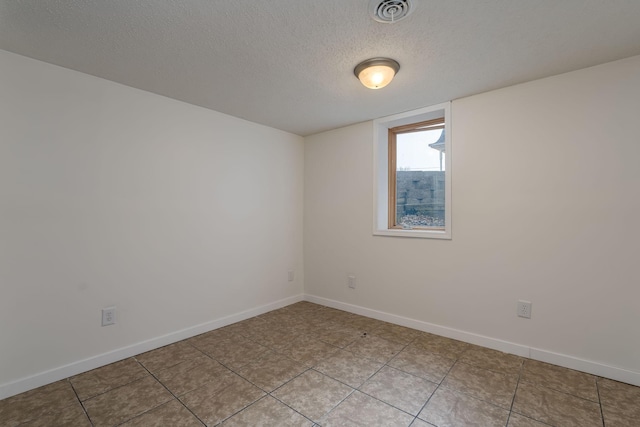 spare room featuring light tile patterned floors, baseboards, visible vents, and a textured ceiling