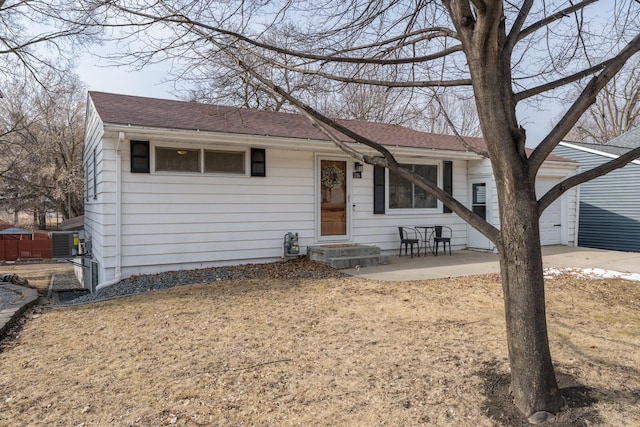 view of front of house featuring central AC unit, a garage, and roof with shingles