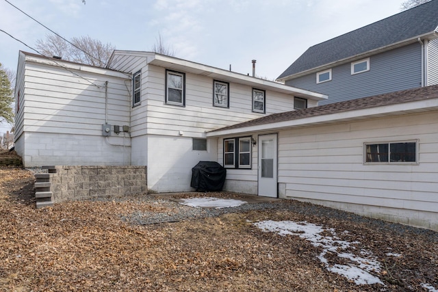 back of property with a shingled roof and a patio