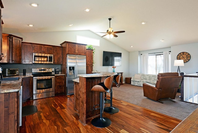 kitchen with stainless steel appliances, dark wood-type flooring, a breakfast bar area, and a center island