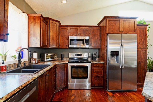 kitchen featuring a toaster, lofted ceiling, dark wood-style floors, stainless steel appliances, and a sink