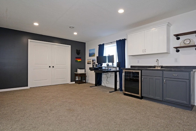 interior space with a sink, wine cooler, light carpet, white cabinetry, and dark countertops