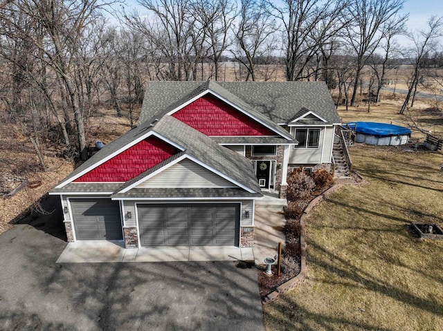 view of front facade with a front yard, an attached garage, a shingled roof, stone siding, and aphalt driveway