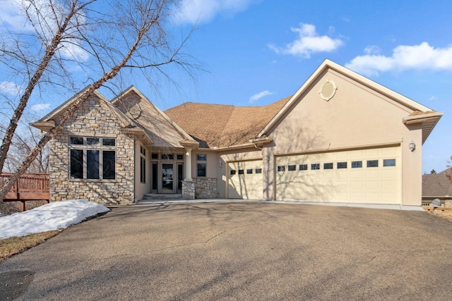 view of front of property featuring stone siding, a garage, driveway, and stucco siding