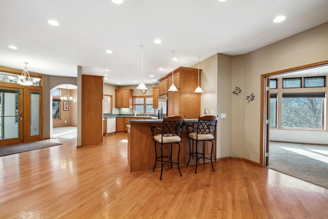 kitchen featuring dishwasher, plenty of natural light, arched walkways, and stainless steel refrigerator with ice dispenser