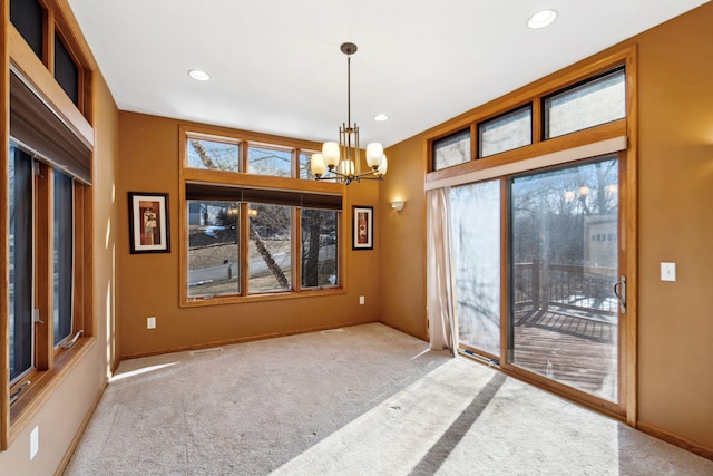 unfurnished dining area with a chandelier, recessed lighting, a wealth of natural light, and carpet