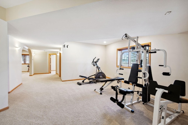 workout room featuring carpet, recessed lighting, arched walkways, and baseboards