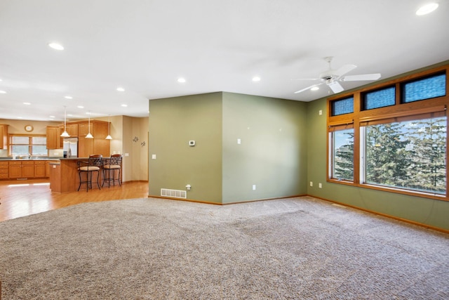 unfurnished living room with light carpet, visible vents, recessed lighting, and baseboards