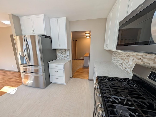 kitchen featuring stainless steel appliances, white cabinets, decorative backsplash, and light countertops