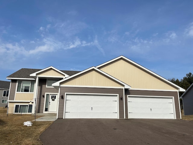 view of front of home with a garage, roof with shingles, and driveway