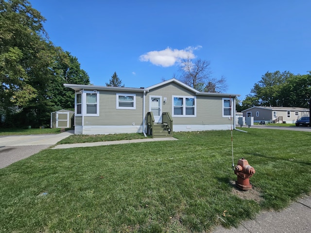 manufactured / mobile home with an outdoor structure, a front lawn, and a shed