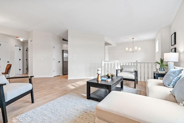 living room featuring light wood-type flooring, baseboards, and an inviting chandelier