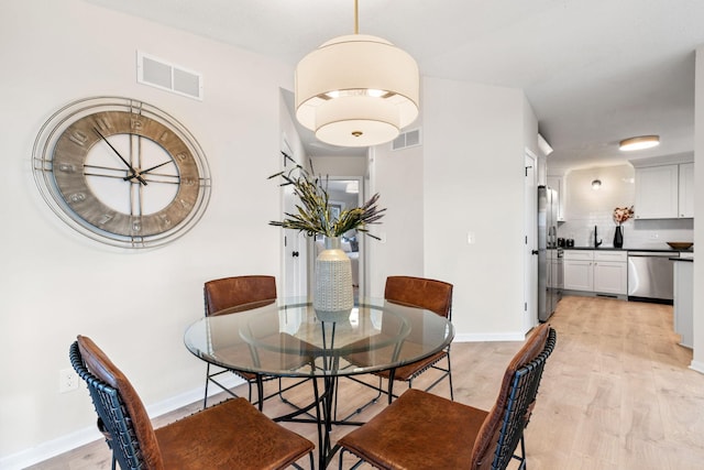 dining area featuring visible vents, baseboards, and light wood-style floors