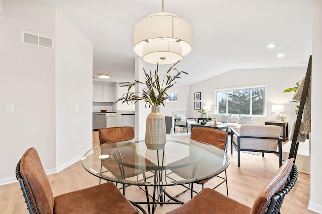 dining area with lofted ceiling, baseboards, visible vents, and light wood-type flooring