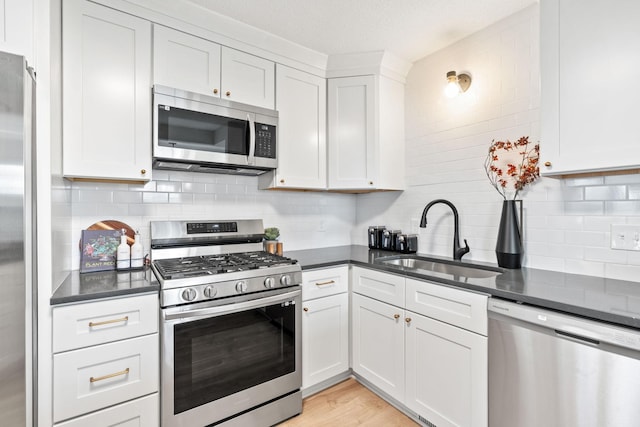 kitchen featuring a sink, stainless steel appliances, dark countertops, and decorative backsplash