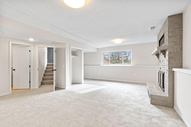 unfurnished living room featuring visible vents, light colored carpet, a brick fireplace, and stairs