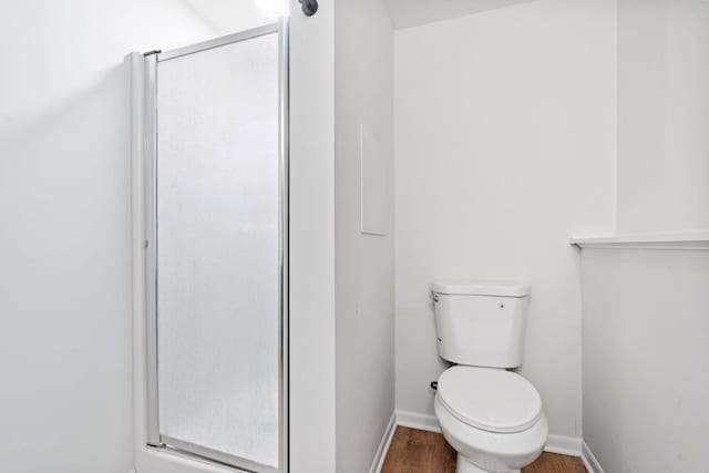 full bathroom featuring a shower stall, toilet, wood finished floors, and baseboards