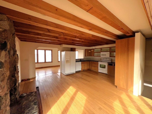 kitchen featuring white appliances, wood finished floors, dark countertops, and beam ceiling