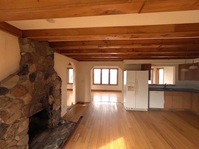 unfurnished living room with a sink, beamed ceiling, and hardwood / wood-style flooring