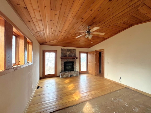 unfurnished living room featuring light wood-style floors, a stone fireplace, baseboards, ceiling fan, and vaulted ceiling