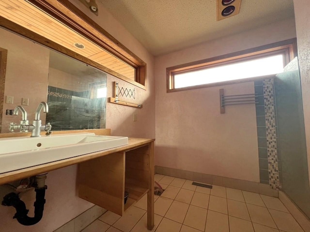 bathroom featuring a sink, baseboards, tile patterned flooring, and a textured ceiling