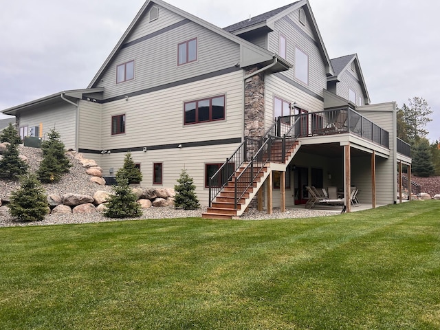 rear view of house featuring a yard, stairs, stone siding, a deck, and a patio area