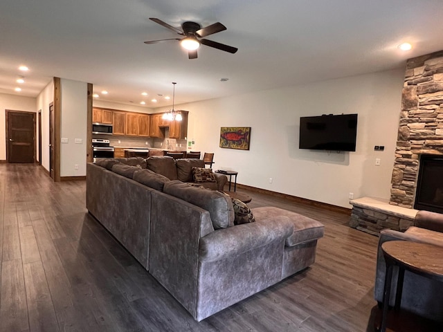 living area with ceiling fan, baseboards, dark wood finished floors, and a fireplace