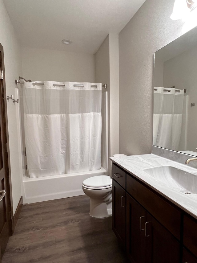 bathroom with vanity, toilet, wood finished floors, and shower / bath combo