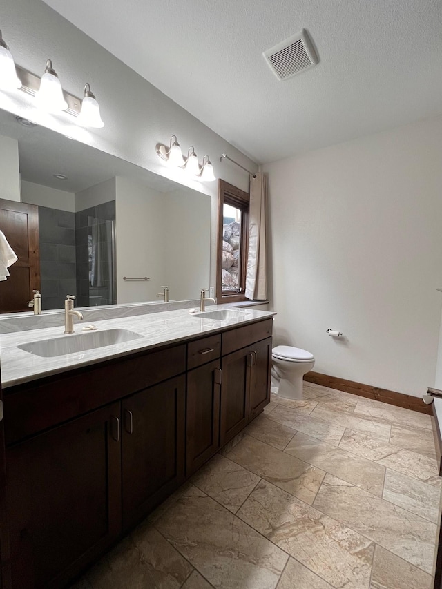 bathroom featuring visible vents, toilet, baseboards, and a sink