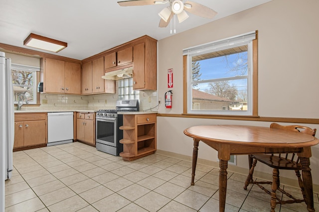 kitchen with white appliances, a ceiling fan, light countertops, under cabinet range hood, and tasteful backsplash