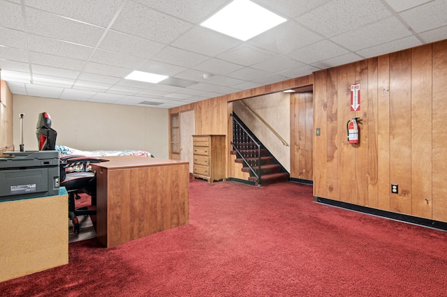 office space with a drop ceiling, baseboards, wood walls, and carpet flooring