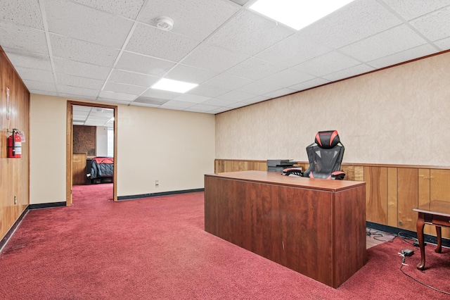 carpeted office with wooden walls, a drop ceiling, and wainscoting