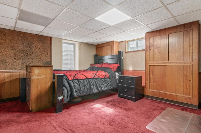 bedroom with wooden walls, a paneled ceiling, and carpet floors