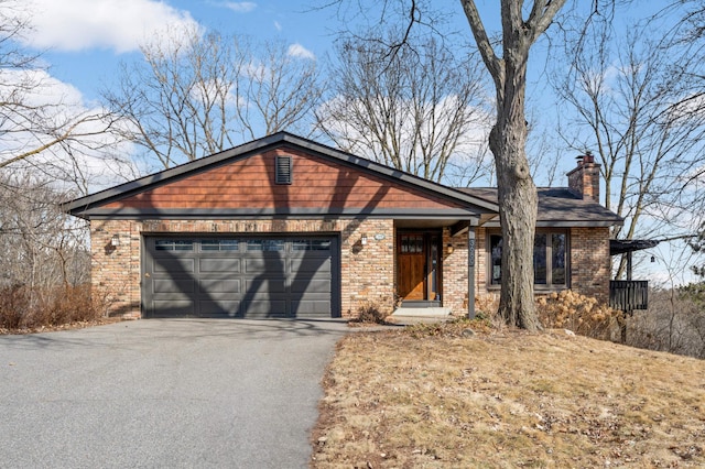 ranch-style house featuring an attached garage, brick siding, driveway, and a chimney