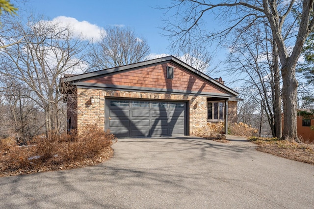 view of front of house with aphalt driveway, a garage, brick siding, and a chimney