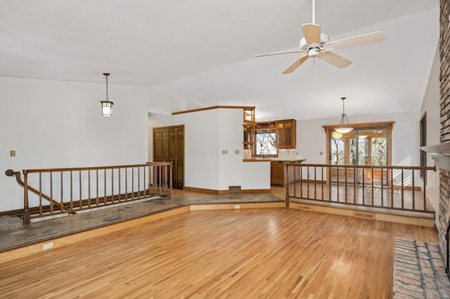 interior space with visible vents, baseboards, vaulted ceiling, wood finished floors, and a ceiling fan