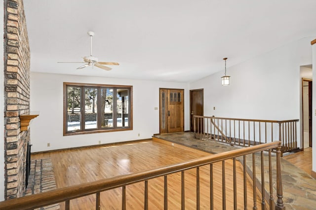 interior space with baseboards, wood finished floors, a ceiling fan, and vaulted ceiling