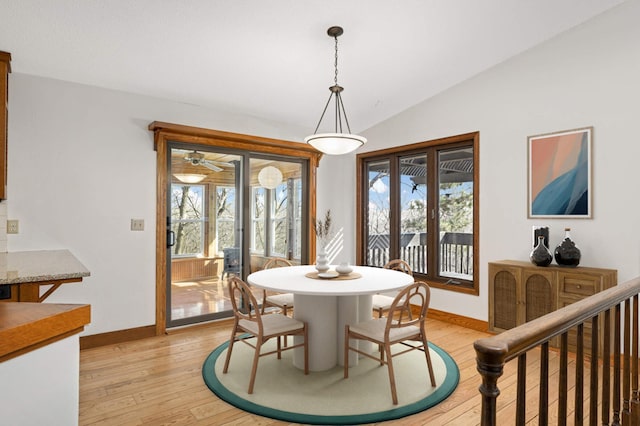 dining room with vaulted ceiling, plenty of natural light, baseboards, and light wood-type flooring