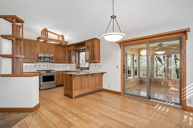 kitchen with decorative backsplash, a peninsula, stainless steel appliances, and glass insert cabinets