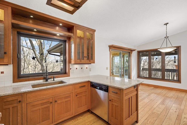 kitchen with light wood-type flooring, a sink, a peninsula, brown cabinetry, and dishwasher