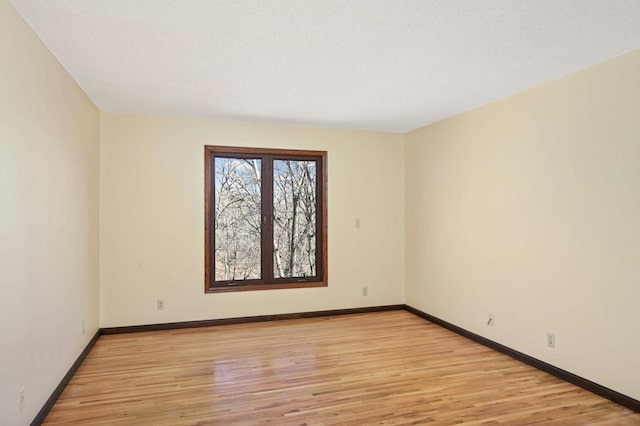 unfurnished room featuring baseboards and light wood-style floors