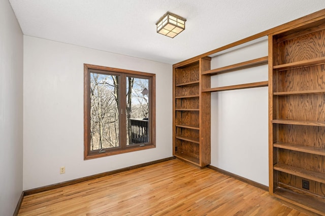 unfurnished bedroom featuring a closet, light wood-style flooring, and baseboards