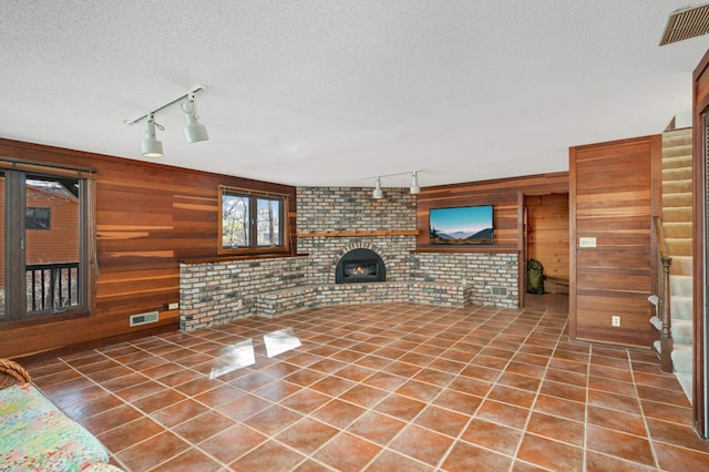 unfurnished living room featuring tile patterned floors, visible vents, a textured ceiling, and wooden walls