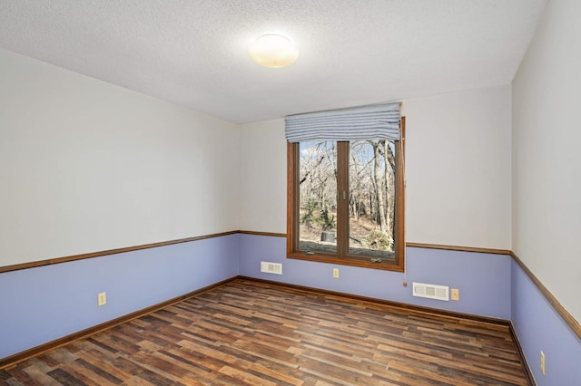 unfurnished room featuring visible vents, baseboards, a textured ceiling, and wood finished floors