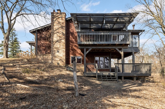 rear view of property featuring a wooden deck and a chimney